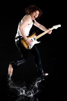 Portrait of dynamic performer with electrical guitar jumping and splashing water