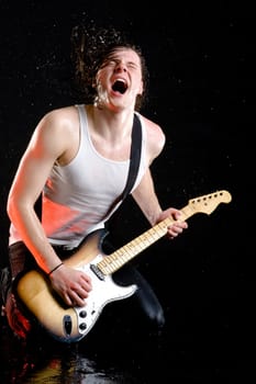 Portrait of wet young guitarist singing rock song in loud manner