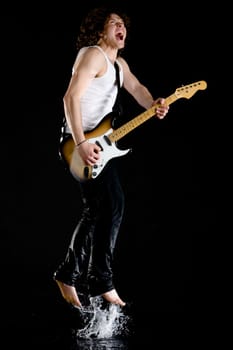 Portrait of dynamic performer playing electrical guitar while jumping above water and singing
