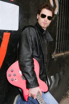 rocker rock star man on black graffiti holding red electric guitar leather jacket