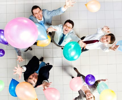 Above view of several successful partners throwing colorful balloons in joy