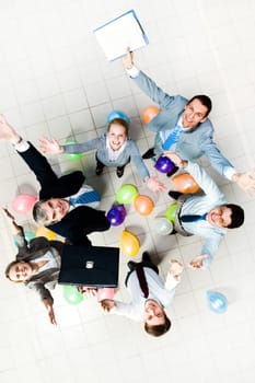 Above view of joyful business people looking at camera with balloons on the floor