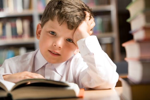 Photo of young boy sitting at the table in the library