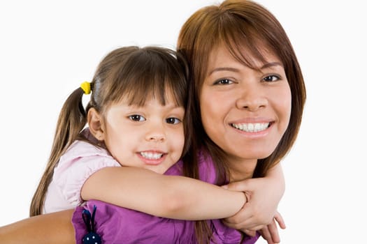 Cute child embracing her beautiful mother and both looking at camera with smiles