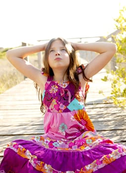 Hippy purple dress teen girl relaxed outdoors, sitting over the park wood