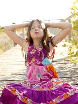 Hippy purple dress teen girl relaxed outdoors, sitting over the park wood