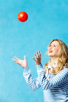 Portrait of young cheerful woman playing with a ball