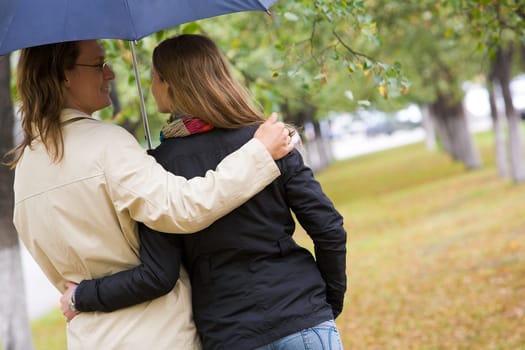 Rear view of affectionate couple walking under umbrella