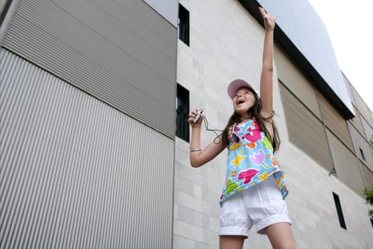 Brunette teen little girl dancing mp3 headphones music in the city