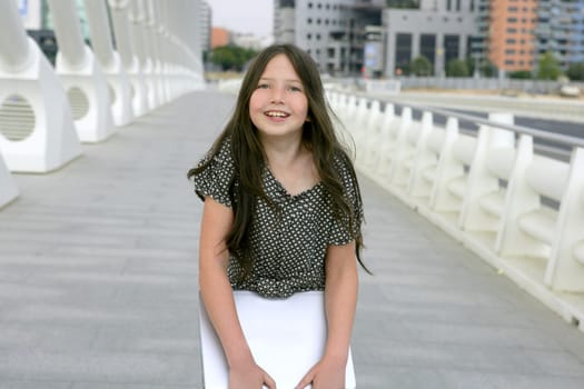 Beautiful little girl with laptop computer downtown city bridge