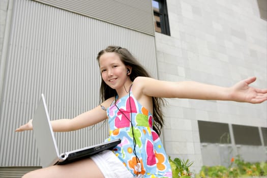 Beautiful brunette little girl teen expression with laptop city outdoor