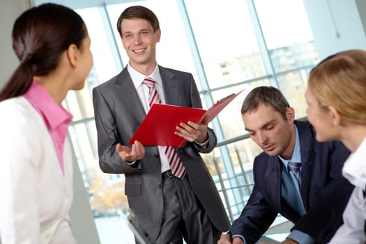 Image of businessman answering questions of colleagues at meeting