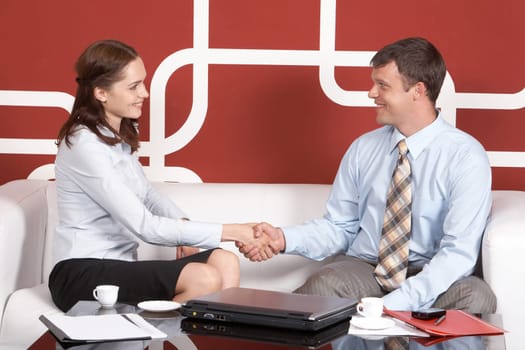 Portrait of business partners handshaking at meeting and looking at each other
