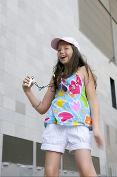 Brunette teen little girl dancing mp3 headphones music in the city