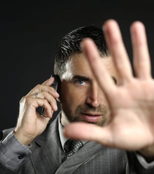 Angry businessman saying stop with hand,talking to a mobile phone