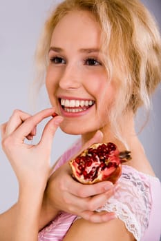 Portrait of a beautiful blonde woman with the pomegranate in her hand