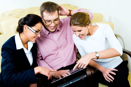 Portrait of three business people looking at the laptop in the conference room