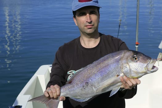 Fisherman showing proud his good catched saltwater fish, over boat