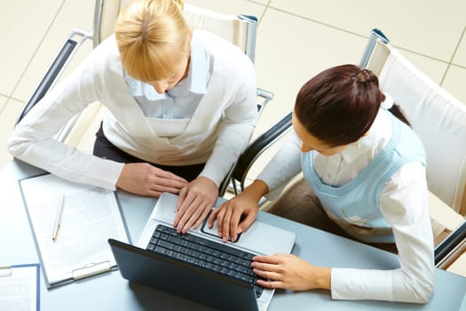 Above view of two businesswomen typing on a laptop