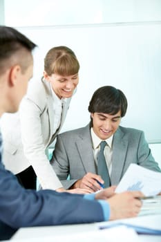 Portrait of smiling partners looking through papers in office