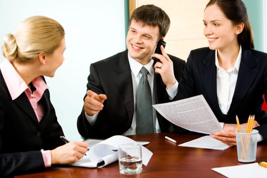Portrait of business man telling something to colleague while calling on the phone with woman sitting near by