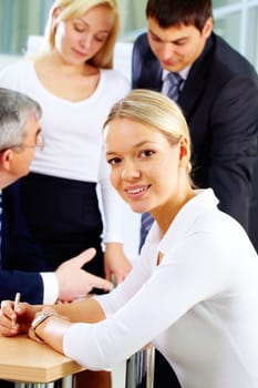 Portrait of a young woman against her colleagues