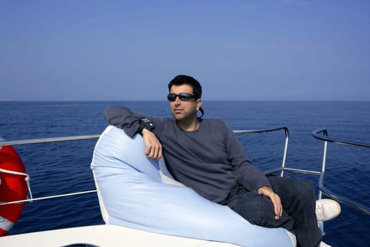 Man on bow boat relaxed on bean bag over blue sea