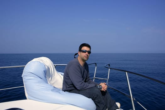 Man on bow boat relaxed on bean bag over blue sea