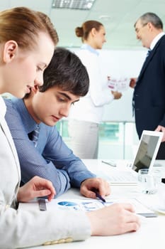Portrait of confident man looking at document with female near by in working environment