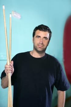 Billiard player man holding two pool sticks over green background