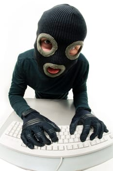 Image of criminal in balaclava pressing buttons of keyboard