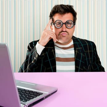 Nerd pensive man with myopic glasses and silly expression searching a solution in laptop computer
