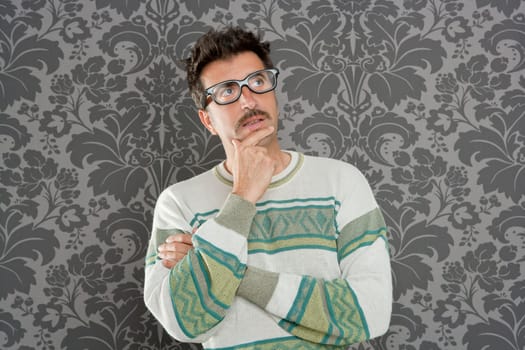 nerd  silly man with pensive expression over retro wallpaper background