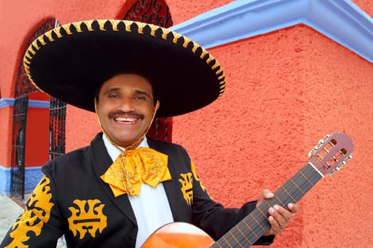 Charro Mariachi singer playing guitar in Mexico houses background