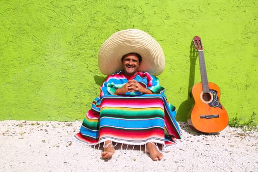 Mexican typical lazy topic man guitar poncho sit in green wall