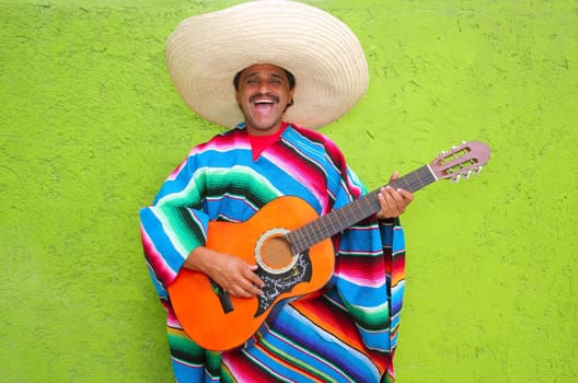 Mexican typical man playing guitar poncho on green wall