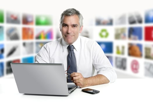 gray hair tv news screen presenter laptop smiling white desk