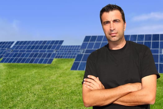 man posing in front of green electric energy solar plates on the meadow
