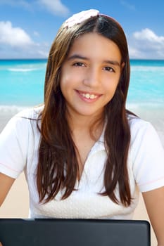 Latin teenager student smiling holding laptop in beach