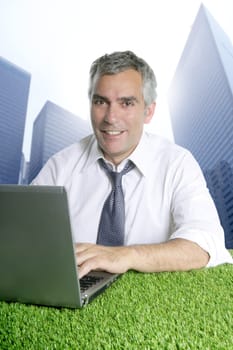 senior businessman working green grass desk computer city modern buildings
