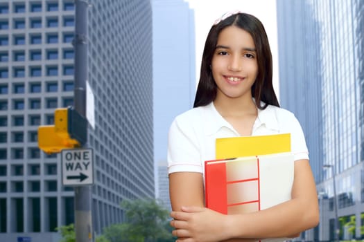 brunette teen  indian latin student holding school books in modern city buildings
