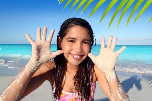 latin indian teen girl playing beach showing sandy hands in Caribbean tropical sea