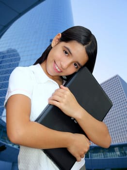 latin teenager brunette student hug laptop modern city buildings