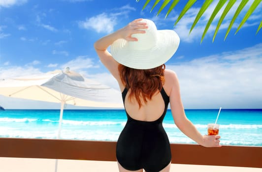 beach hat rear view woman cocktail tropical beach black swimsuit
