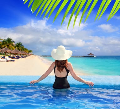 black swimsuit woman rear view in a pool with direct view to tropical Caribbean sea