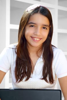 Latin teenager student smiling holding laptop indoor white house