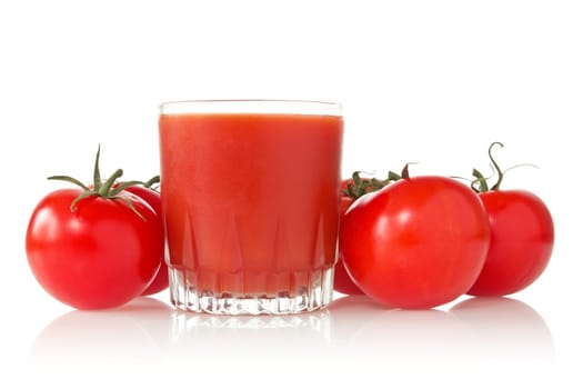 ripe tomatoes and glass of tomato juice over a white background