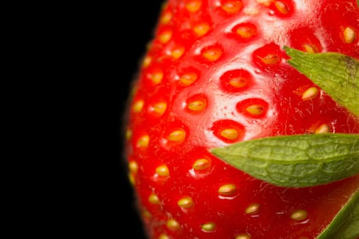 Macro view of fresh strawberry on a black background. Strawberry is in the right half of the photos.
