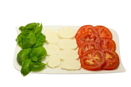 Tomato, fresh basil leaves and mozzarella in a white plate.