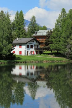 Two small house reflecting in the white lake by summer, Crans Montana, Switzerland